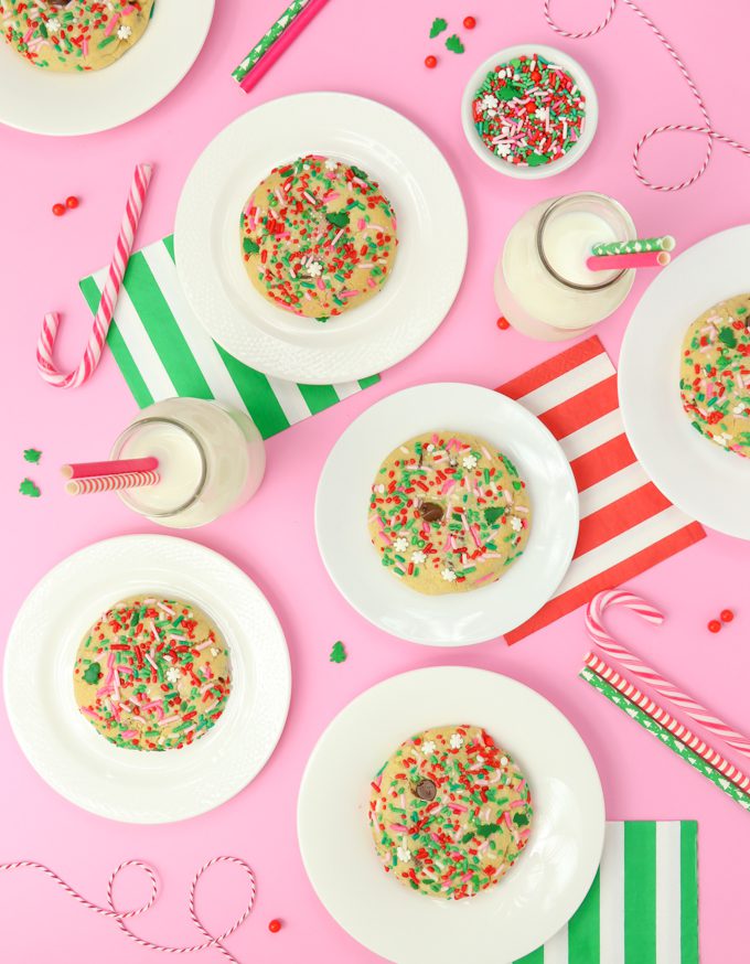 chocolate chip Christmas cookie son pink backdrop with one hand