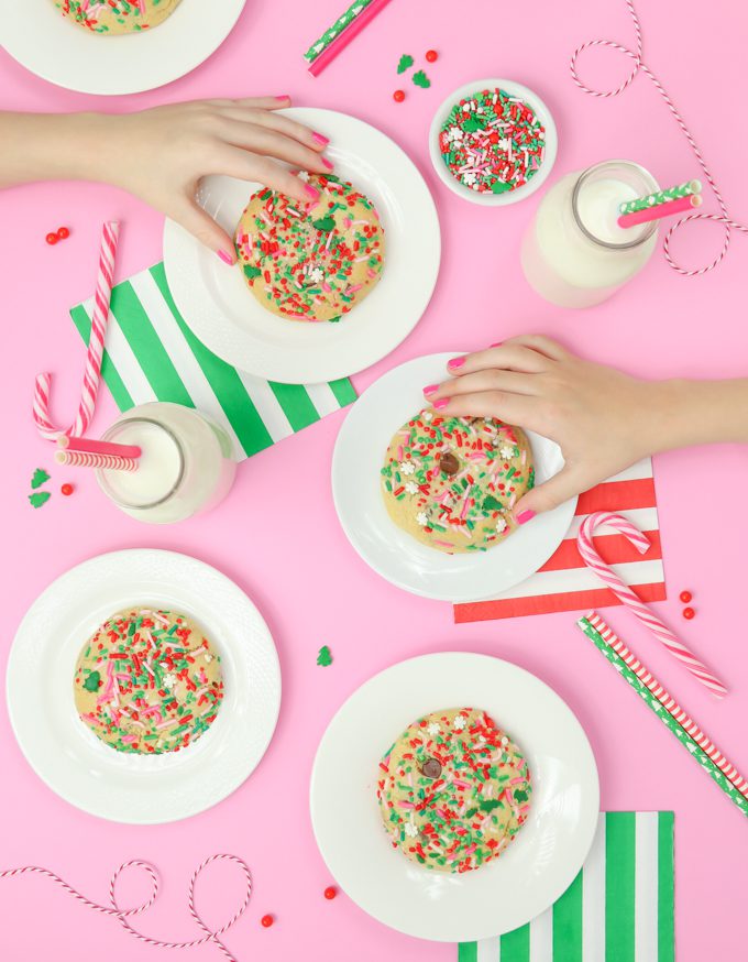 chocolate chip Christmas cookies on pink backdrop with two hands