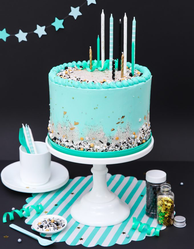 mint blue cookies and cream cake on white stand with candles