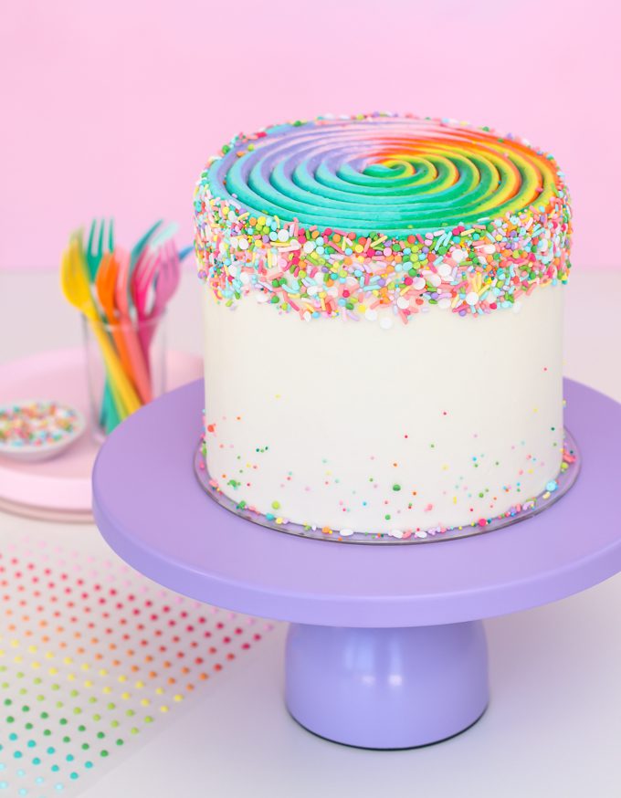 Rainbow swirl cake on purple cake stand.