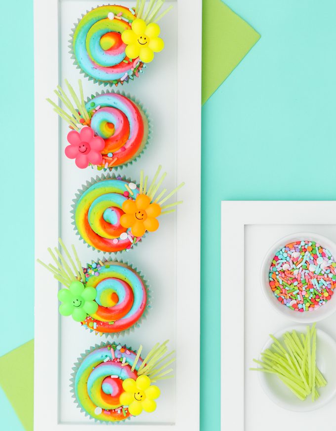 Rainbow swirl cupcakes with edible grass.
