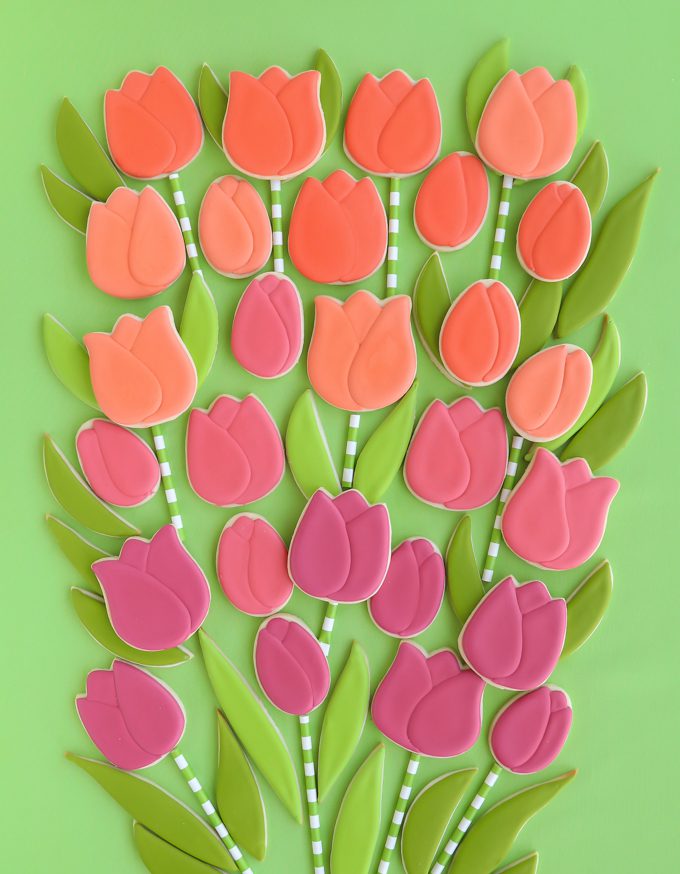 Tulip cookies with leaves on green backdrop.