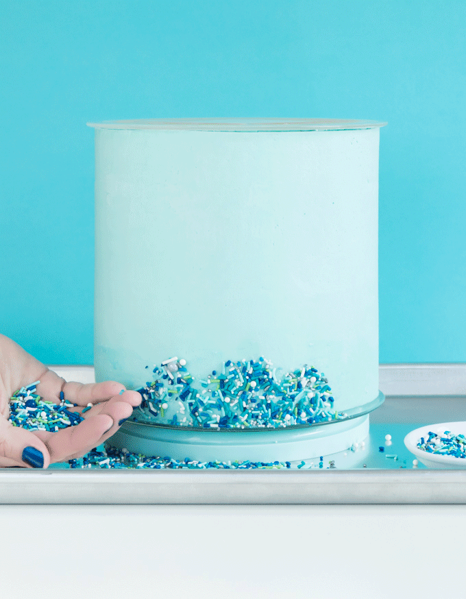 GIF of adding sprinkles to the side of a cake.