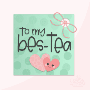 Clipart of a square tag with a hole for a pink bow with a green circle print on it with 2 pink hearts and the words to my bes-tea written in black.
