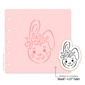 Clipart of a black and white drawing of a bunny head with 1 ear pointing up and the other folded down wearing a flower crown and pink stencil.
