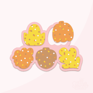 Clipart of thanksgiving frosted crackers shaped like a yellow leaf, orange pumpkin, orange turkey, yellow corn and brown acorn all covered in round sprinkles of the same colours in front of a pink cookie cutter.