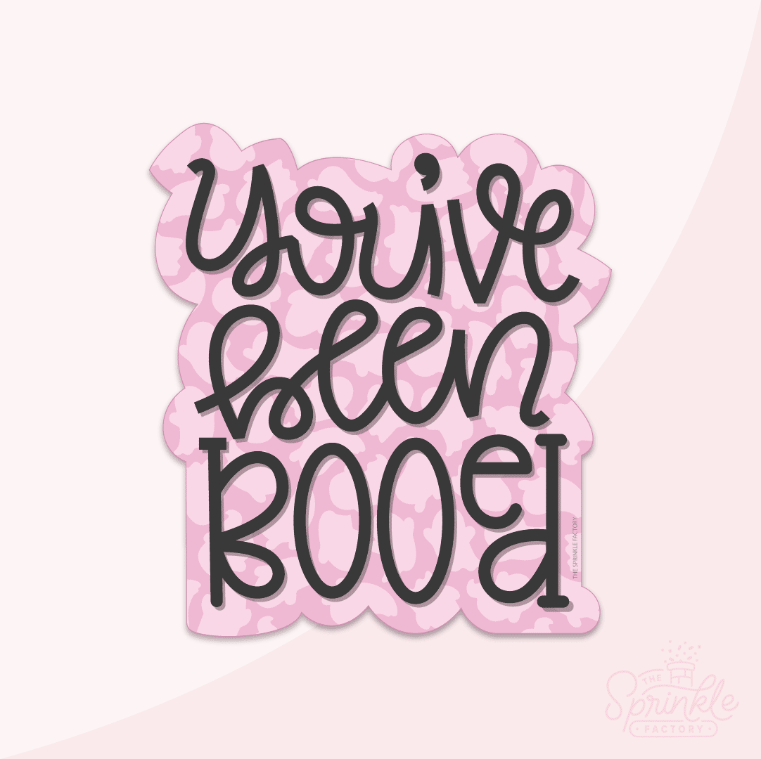 Graphic image of a lettered you've been booed cookie cutter with a pink ghost print background.